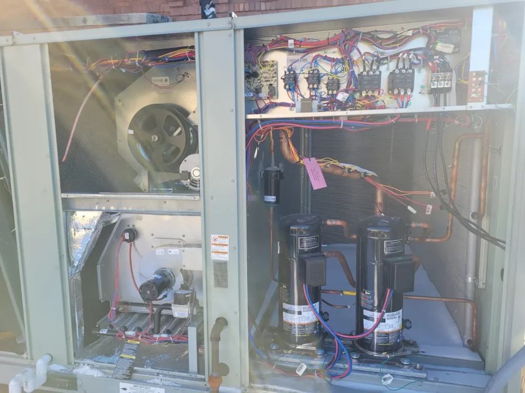 The inside of a commercial rooftop unit, compressors and controls