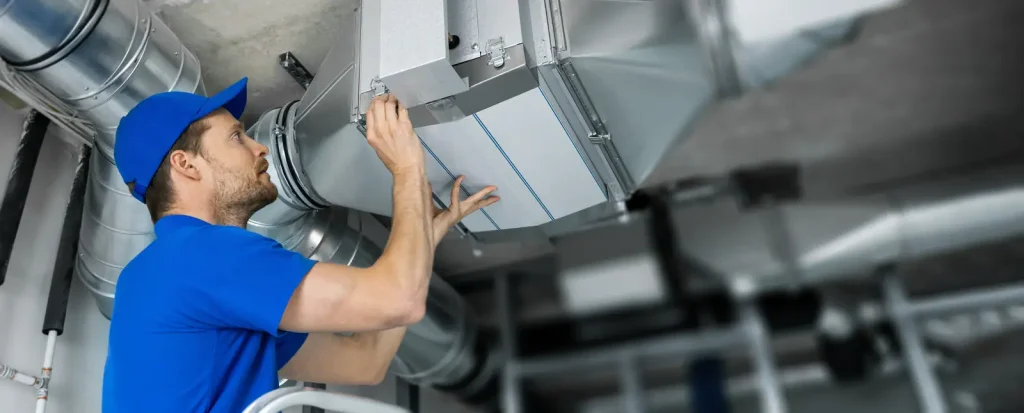 A technician fitting a section of ductwork